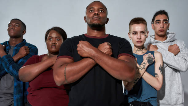 Young multiracial crowd standing side by side with hands crossed on chest against light background and looking above camera, widescreen. Stop racism concept