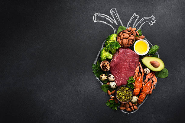 Meat, fish, nuts, fresh vegetables and greens are products for improving the work of the heart. A heart drawn with chalk on a blackboard. Healthy food.