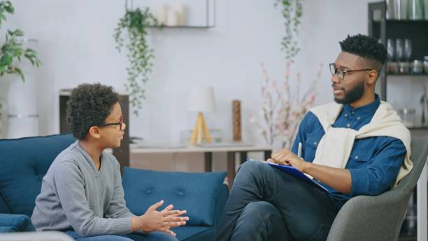 Friendly school psychologist talking to little boy, mental health assessment, support