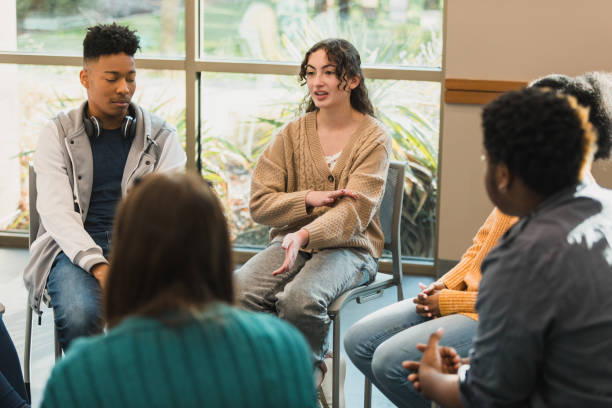 Diverse group of teenagers sitting in a circle, engaged in discussion and sharing experiences. Mental health support and emotional wellbeing.