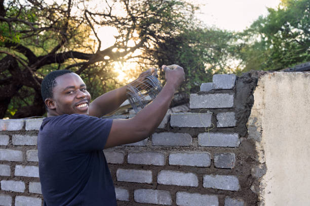 bricklayer african men, using metal masonry reinforcement to reinforce bricks, building a wall at sunset outdoors