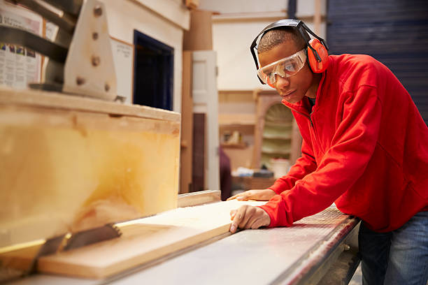 Apprentice Using Circular Saw In Carpentry Workshop