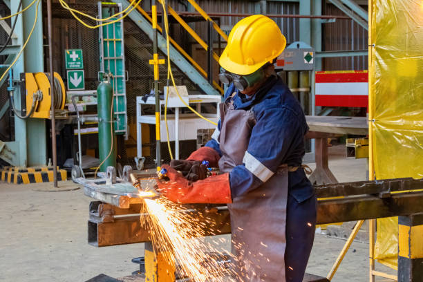 Woman African gas welder in a factory cutting some metal